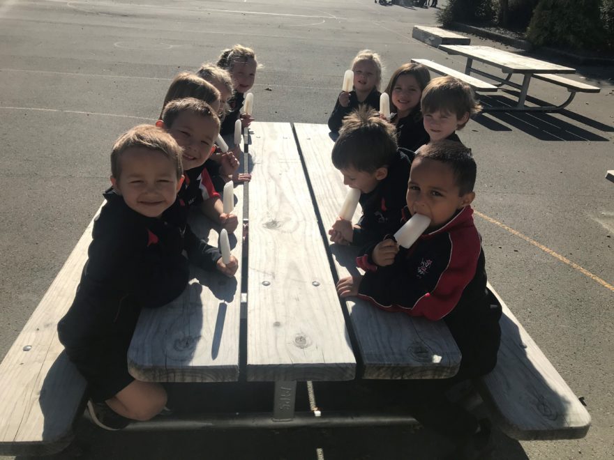 School kids eating ice blocks.