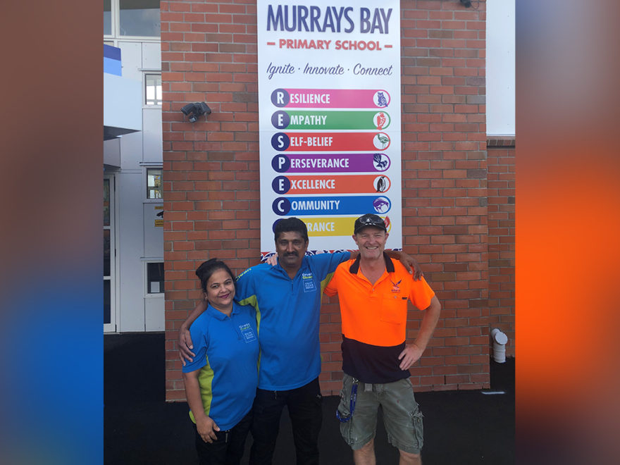 Cleaners and property manager standing outside school.