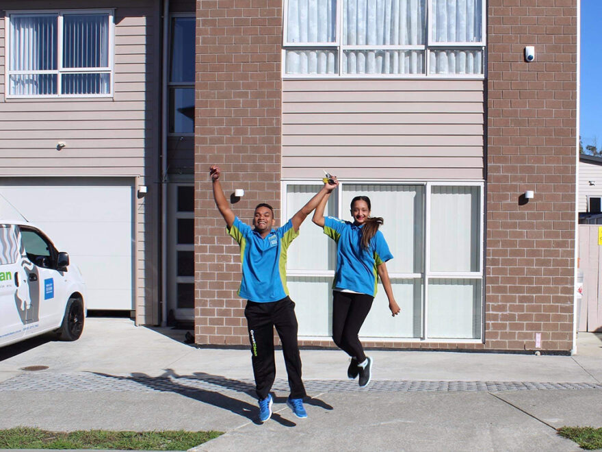 Cleaners jump in the air outside their new home.
