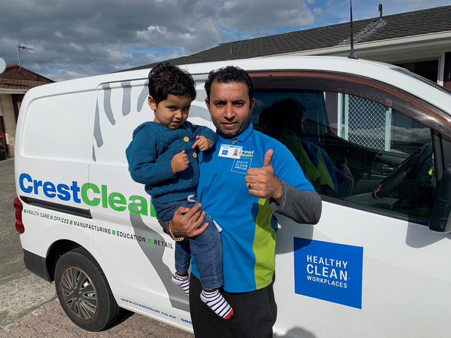 Cleaner holding his son and giving thumbs-up.