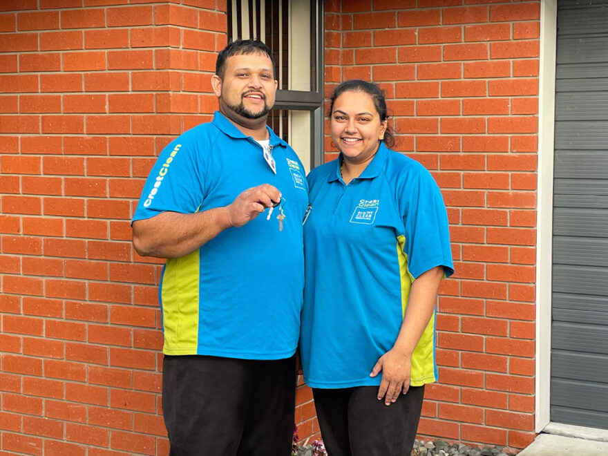 Cleaners hold keys outside house.