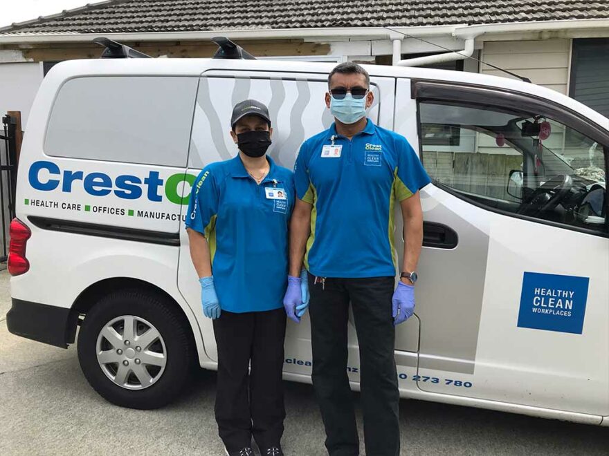 Cleaners wearing masks, standing by their van.