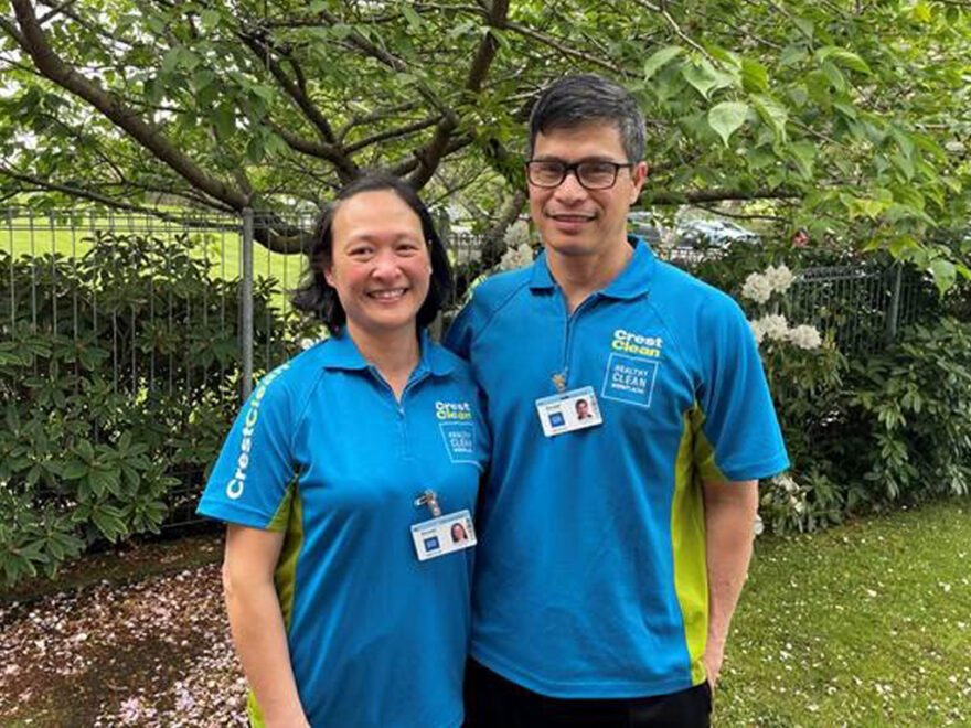 Husband and wife cleaners standing under a tree.