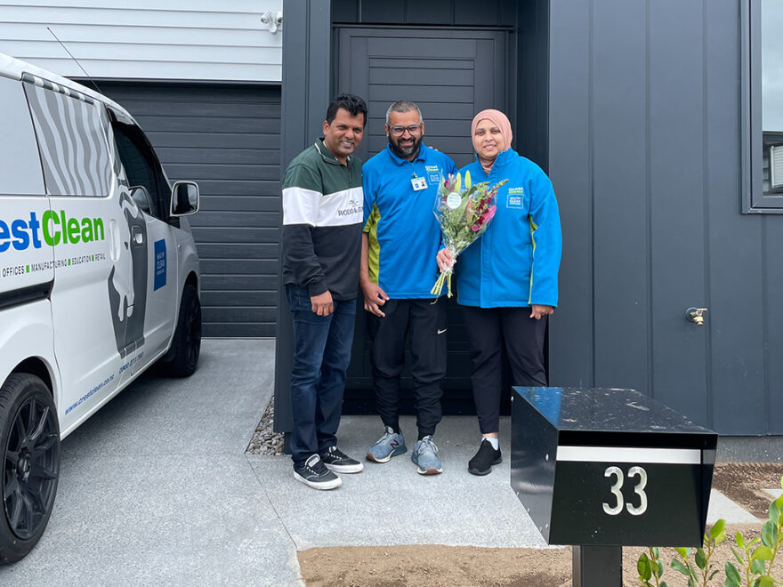 Cleaners holding a bunch of flowers outside their home.