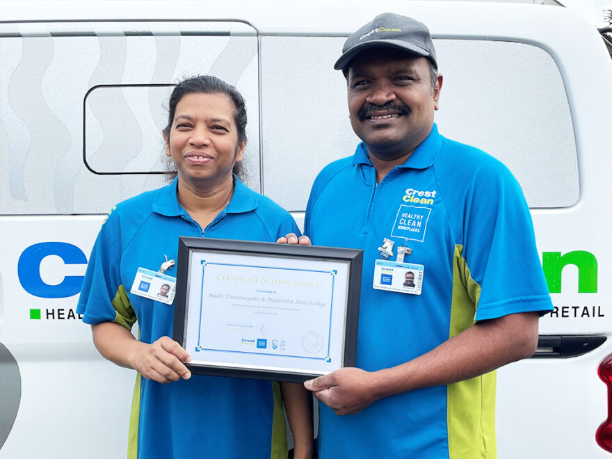 Cleaning couple holding framed certificate.