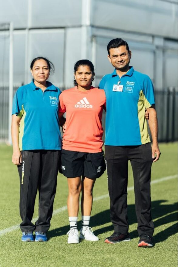 Cricketer standing with her arms around her parents.