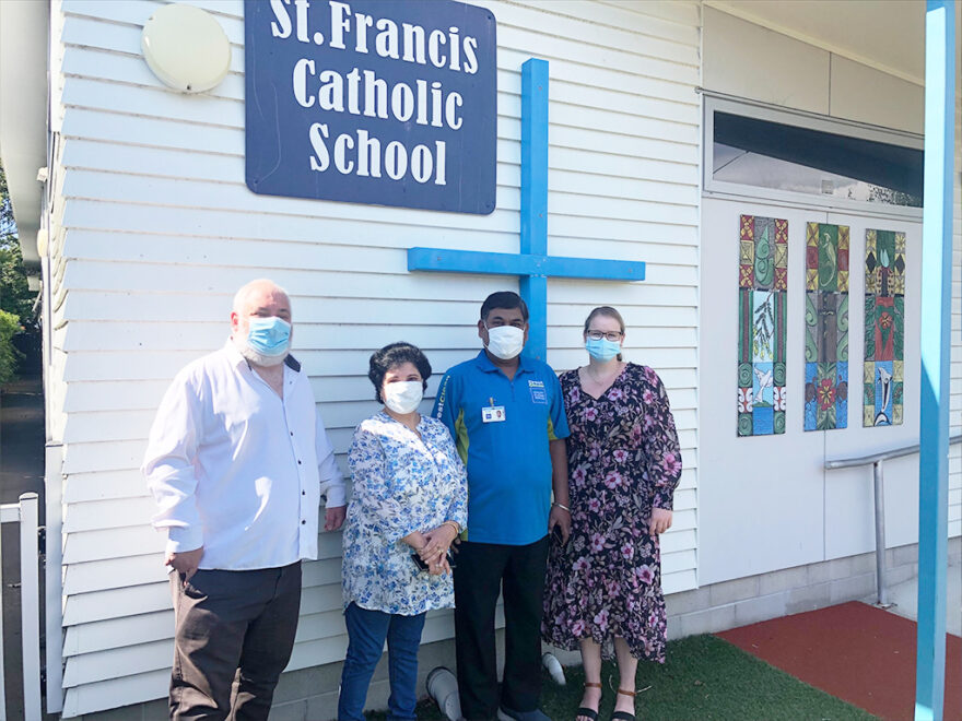 Group of people standing by a school sign.